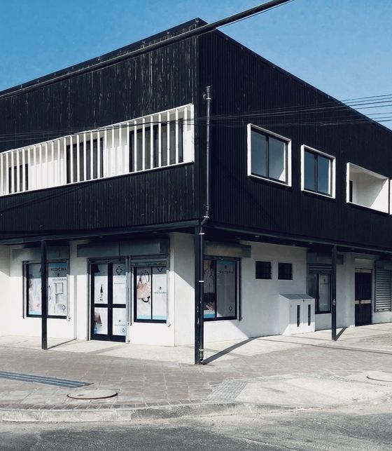 Fachada del Centro Médico Carampangue en Monsalve 102: edificio de dos pisos revestido en madera oscura, en una esquina, un día soleado.