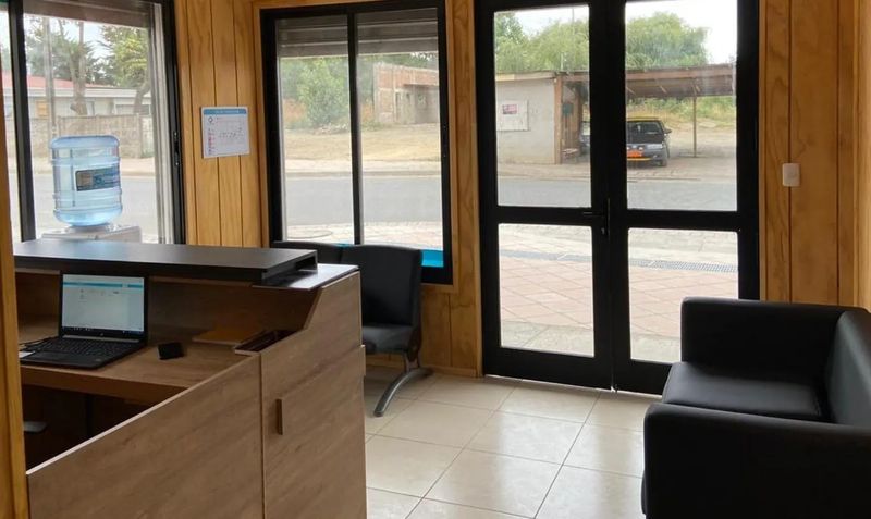 Sala de espera del centro, revestida en madera, con ventanales hacia la calle y sillones negros.