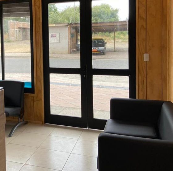Sala de espera del Centro Médico Carampangue: muros de madera, sillones y la puerta de vidrio hacia la calle Monsalve.
