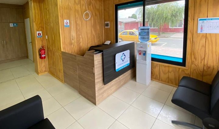 Recepción del Centro Médico Carampangue: mesón de madera, dispensador de agua y ventanal hacia la calle.
