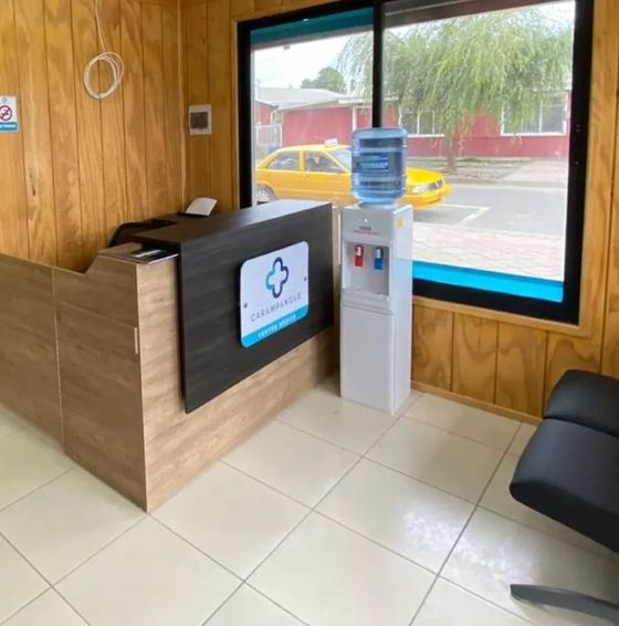 Recepción del Centro Médico Carampangue: mesón de madera con el logo del centro y un ventanal hacia la calle Monsalve.