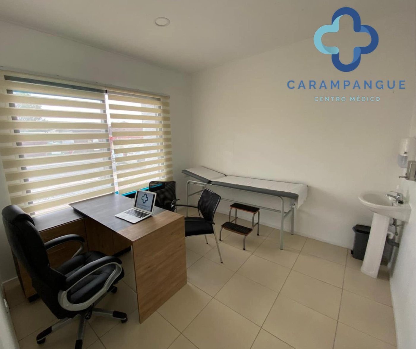 Box médico con camilla, escritorio y ventanal con luz natural