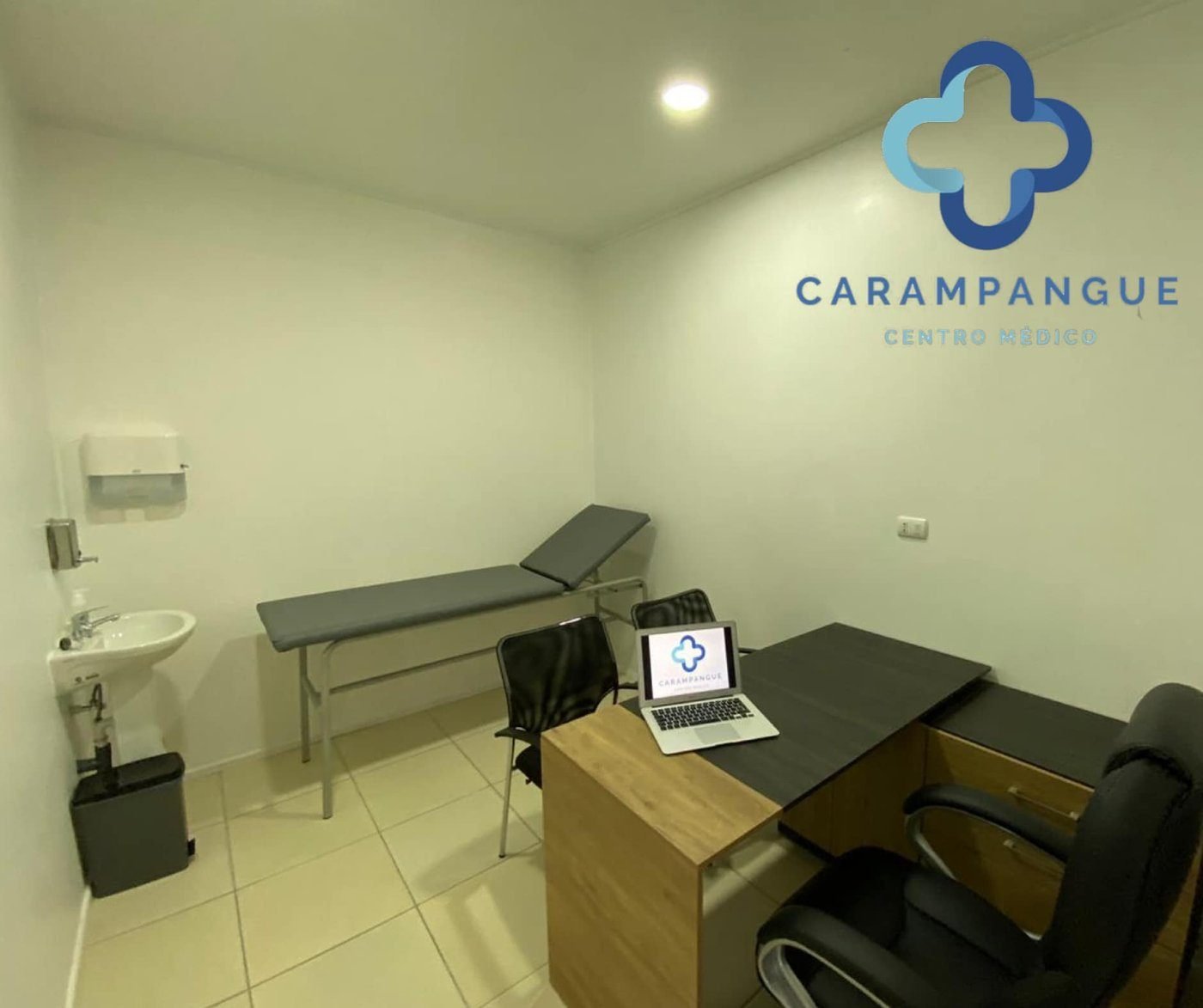 Box de atención médica con camilla, escritorio y lavamanos